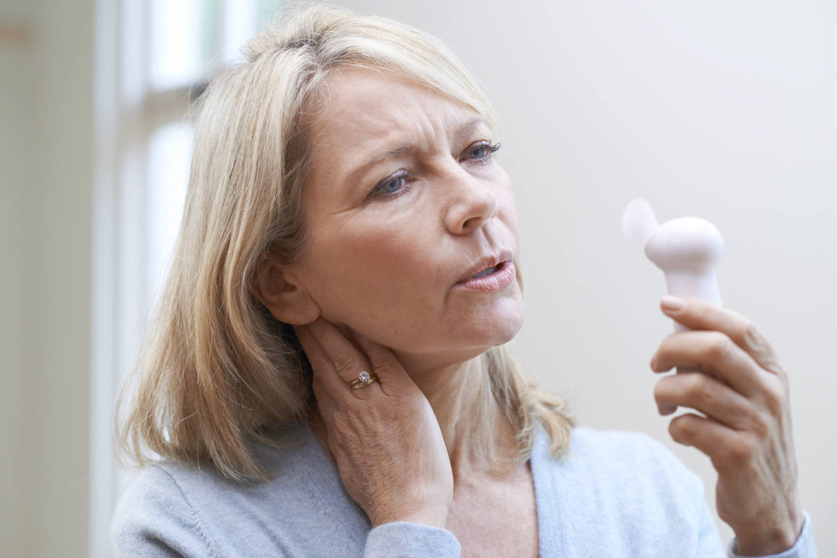 Mature Woman With Fan Experiencing Hot Flush From Menopause | Symptoms of Menopause And How To Treat Them