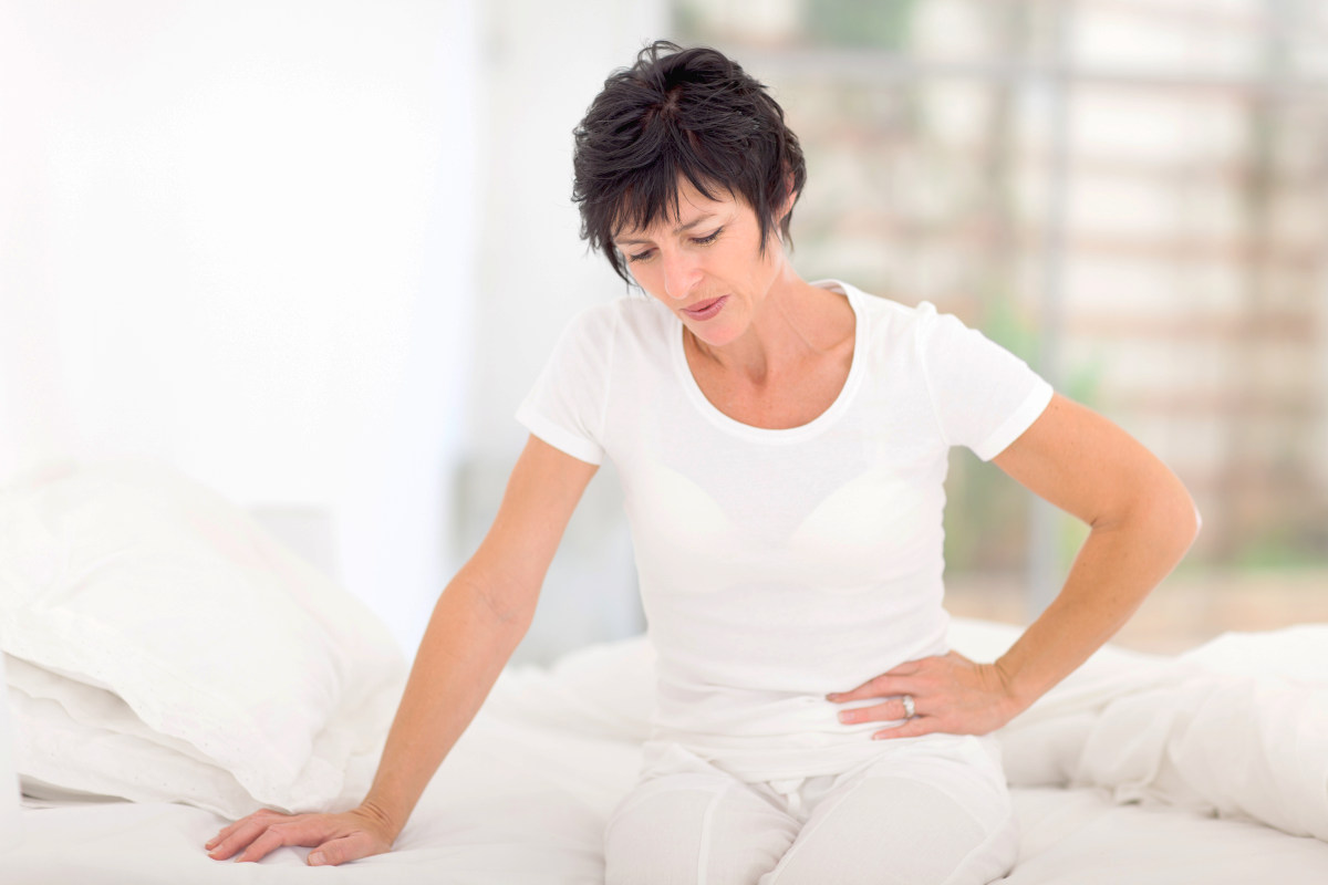 Mature woman sitting on bed and having stomach ache | Everything You Should Know About Vaginal Dryness During Sex