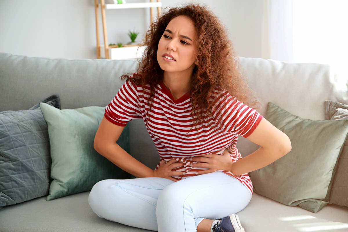 African-American woman suffering from abdominal pain at home | What Happens When Estrogen Levels Are High? | High Estrogen | high levels of estrogen