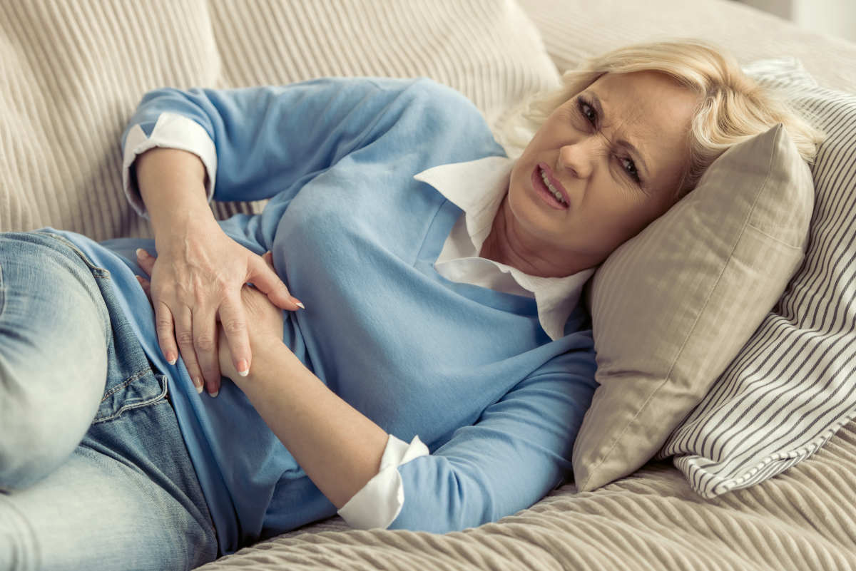 Beautiful tired old woman in casual clothes is having a stomach ache while lying on couch at home | What Is Estrogen Dominance And What To Do About It? | estrogen dominance diet