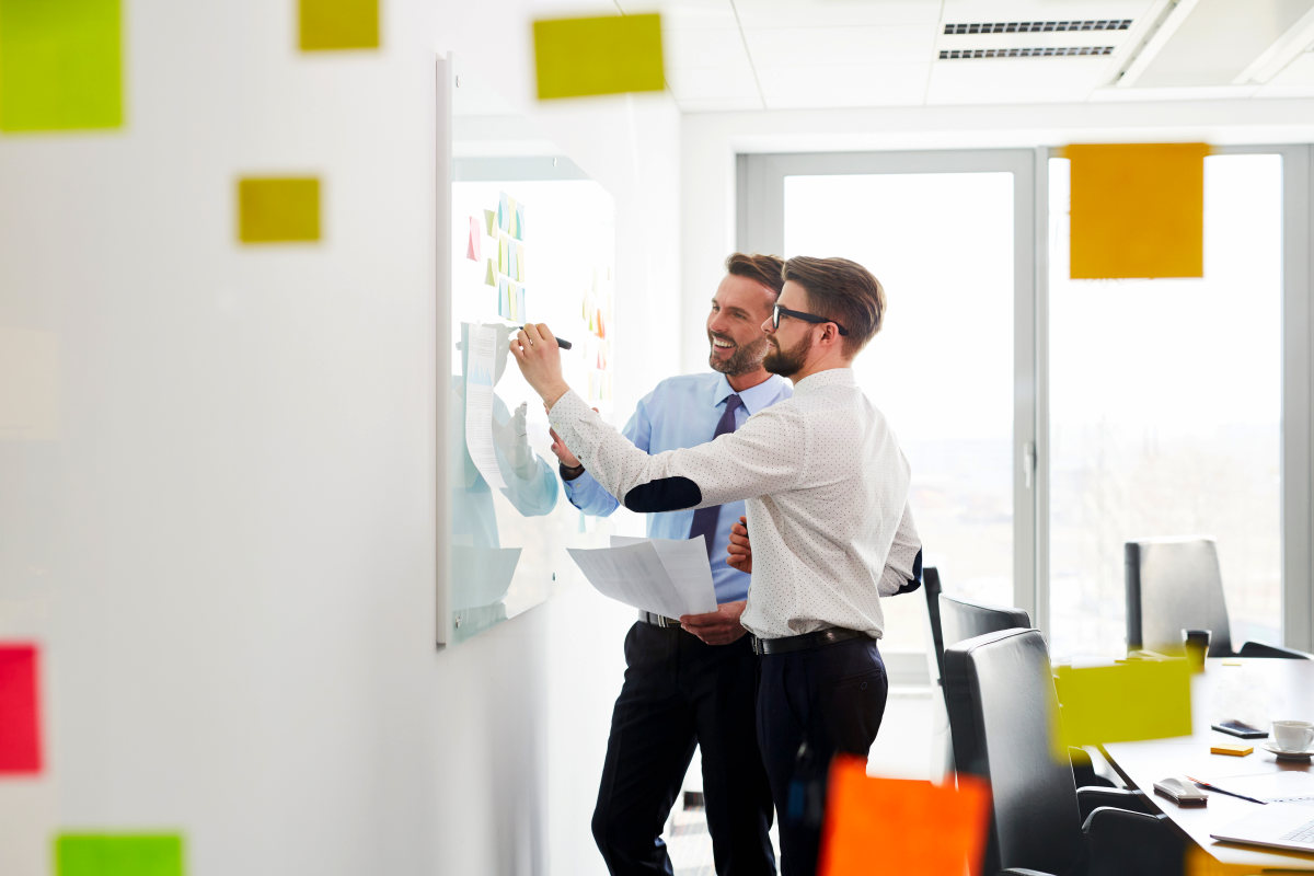 Two businessmen working at office planning new strategy on whiteboard | Overcoming Anxiety: Anxiety Symptoms And How To Fight It | overcoming relationship anxiety