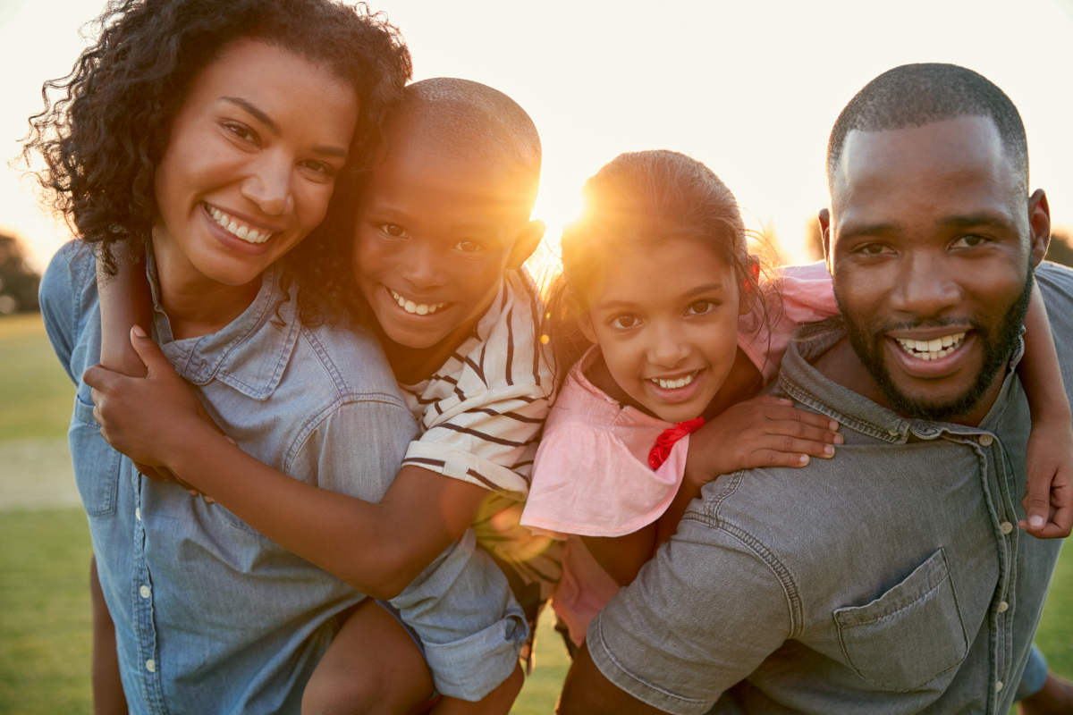 Young black couple with children on piggyback | Ways To Reverse Aging Symptoms and Signs | facial plethora, how to reverse aging caused by stress