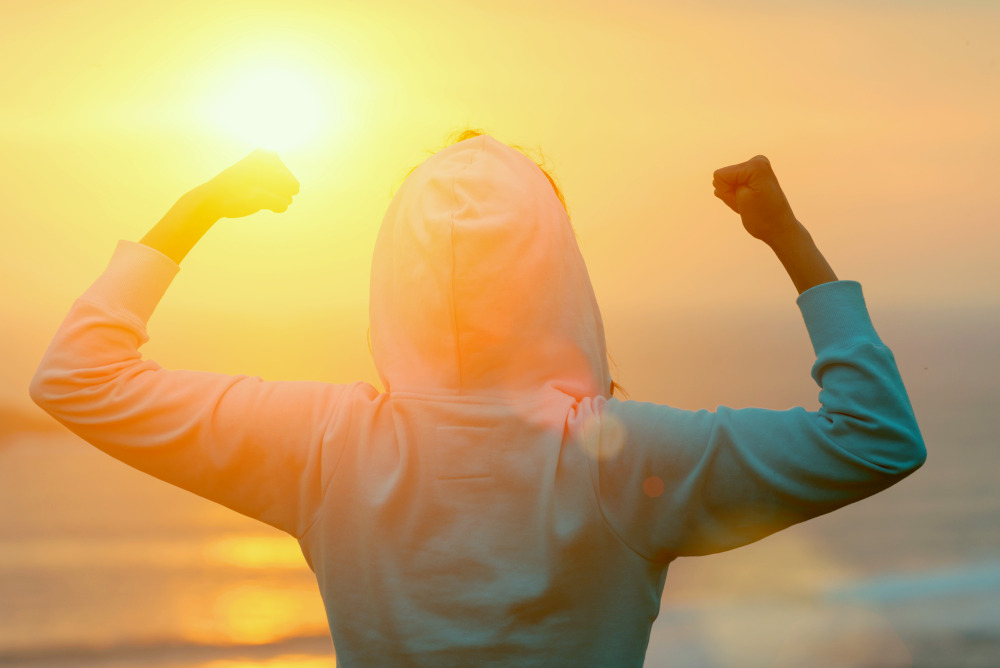 Strong motivated woman celebrating workout goals towards the sun | What Are Collagen Peptides? | collagen peptides benefits