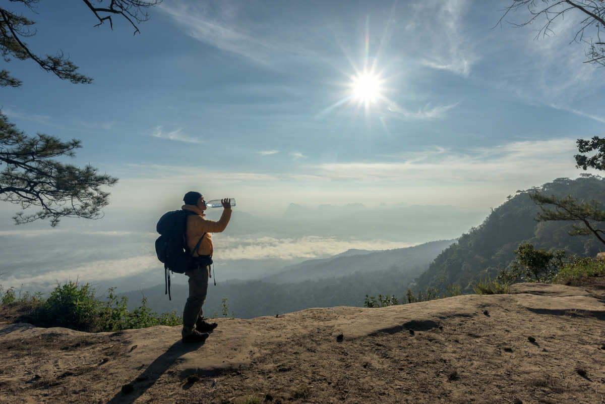 Traveler relaxing and drinking bottled water with backpack on cliff | Wilderness Survival | How To React In A Hiking Accident Before Help Arrives | wilderness survival kit
