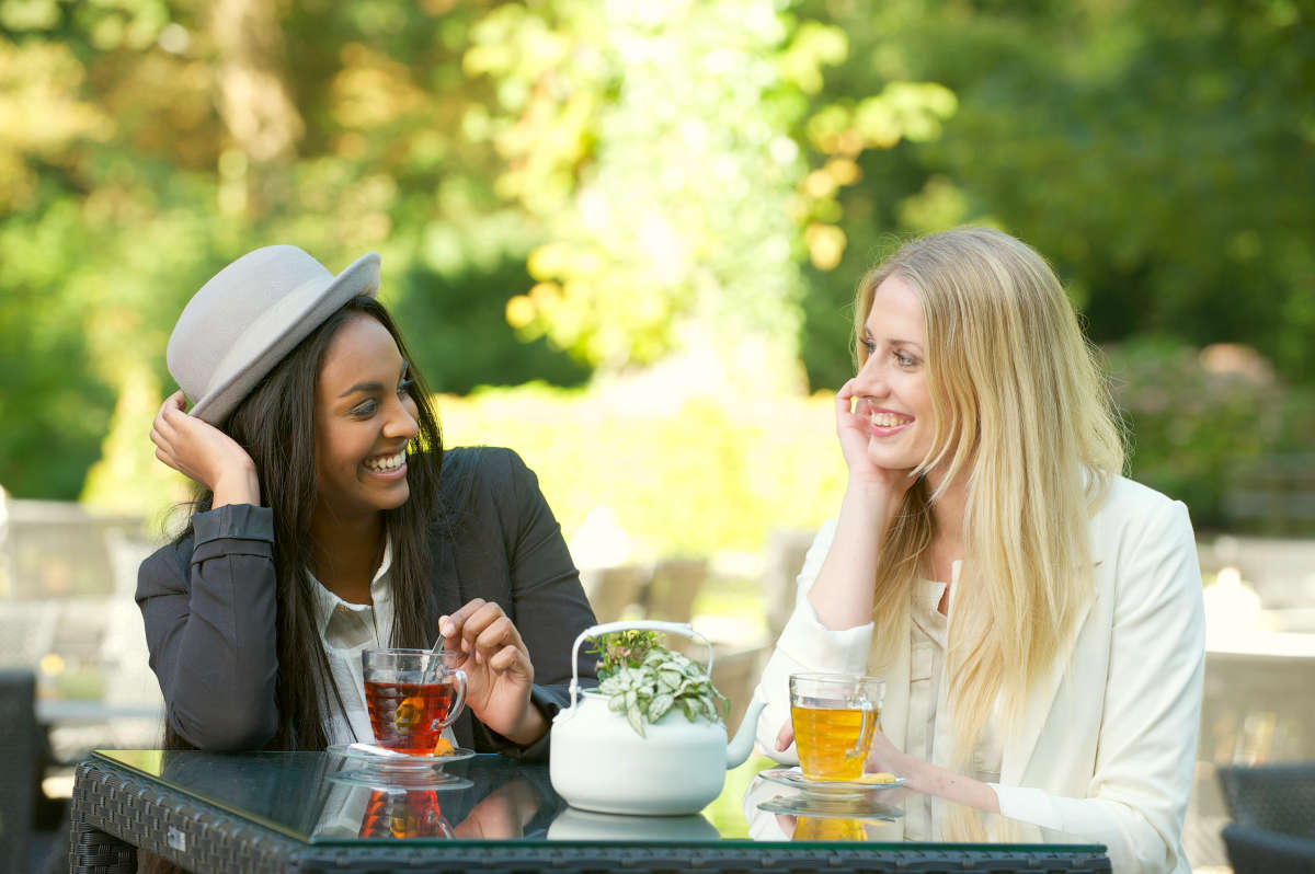 Two beautiful women drinking tea outdoors | Tips To Maintain High Energy Levels On A Busy Workday | energy work