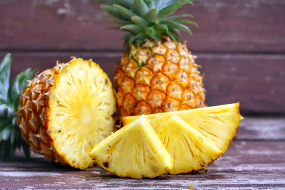 Sliced and whole of Pineapple(Ananas comosus) on wooden table background | Best Fruits For Hypothyroidism | Hypothyroid Diet Food | foods to eat with hypothyroidism