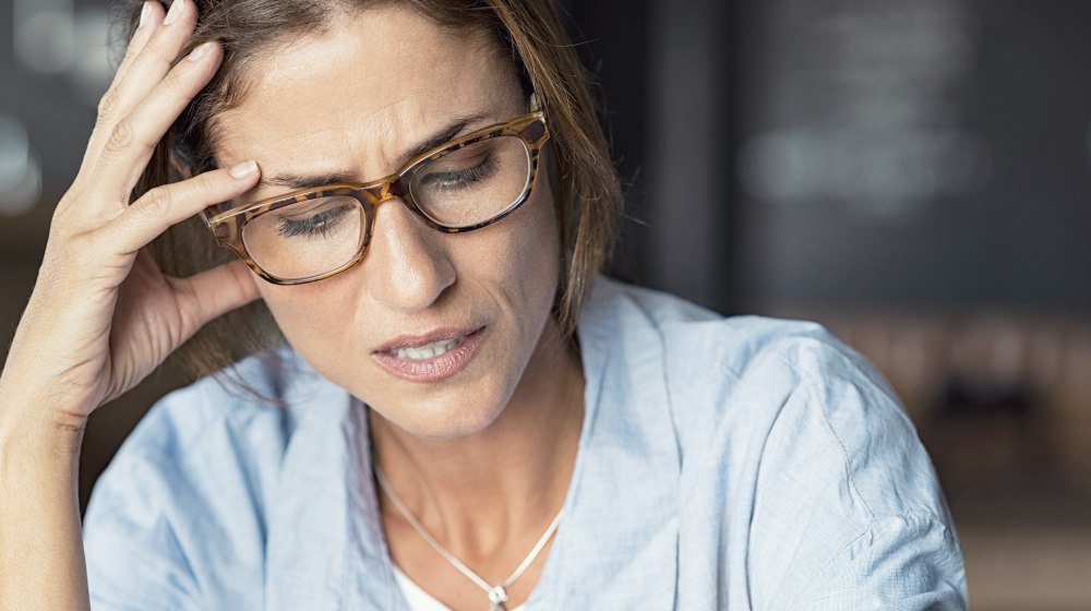 stressed woman with hand on her head | Brain Fog: Top Causes, Symptoms and Treatment | brain fog | physical and mental fatigue