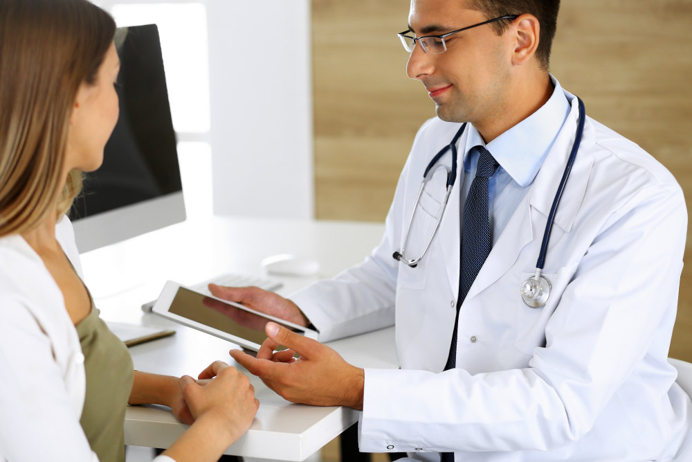 Doctor and patient discussing medical exam results while sitting at the desk in clinic | How Mobile Tech Shapes The Future Of Telehealth | mobile health | medical apps for patients