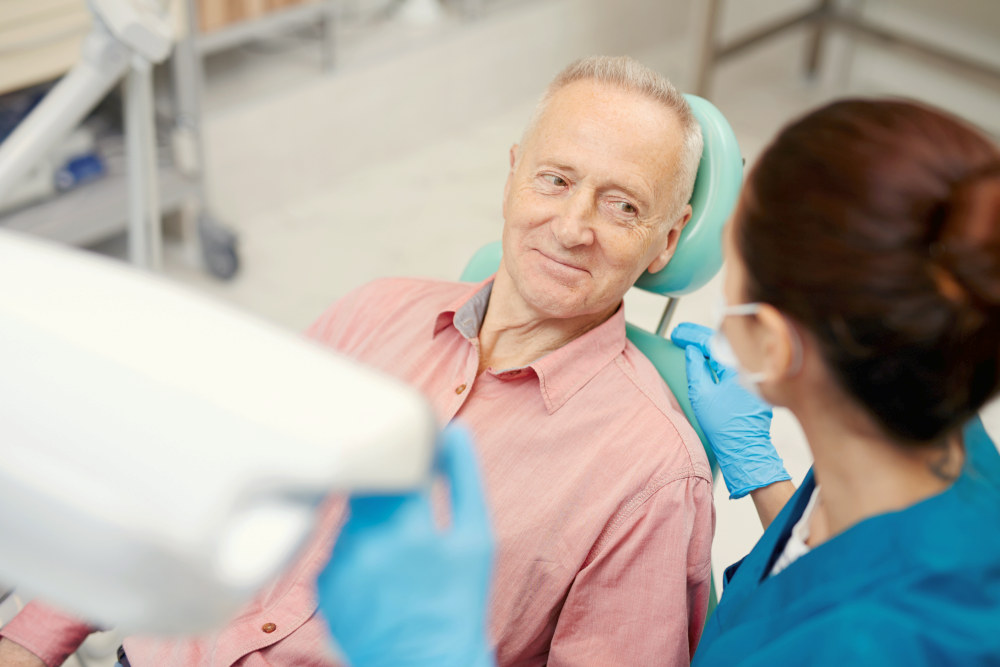 Senior man looking at his dentist and listening to her advice after oral check-up | How To Feel Better in 2020: Resolutions And Tips For Aging Well | best diet for men over 50