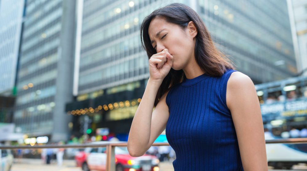 woman coughing outdoor | Symptoms Of Thyroid Cancer To Watch Out For | symptoms of thyroid cancer | thyroid cancer stages