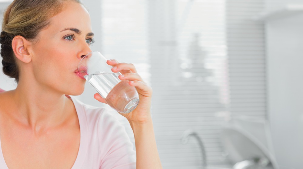 blonde woman drinking water | Thyroid Neck Check: A Step-By-Step Guide For Thyroid Disorders | thyroid neck check | hypothyroidism symptoms