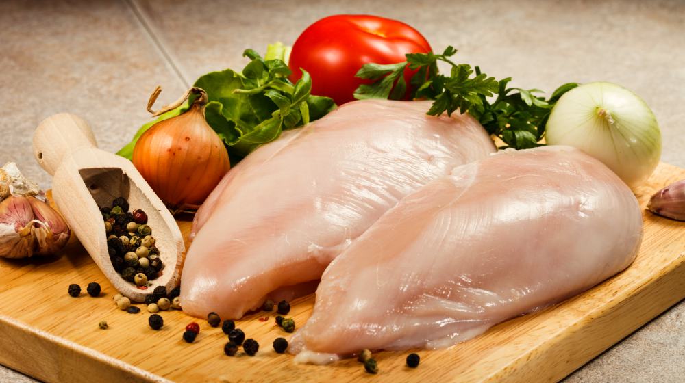 raw chicken breast on cutting board | Muscle Building Diet: Foods to Eat and Avoid | muscle building diet | muscle building diet plans