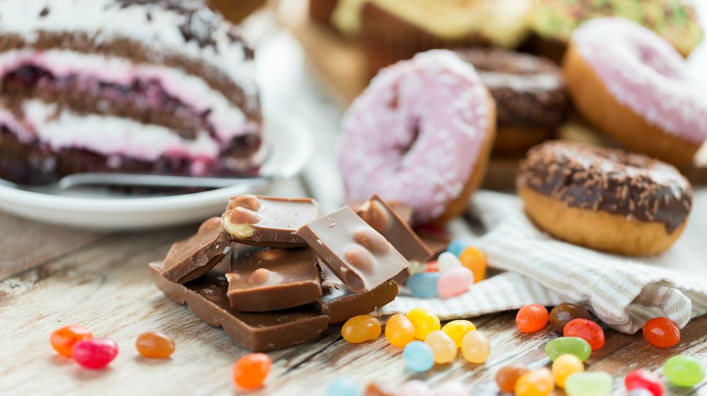 Candy bars, doughnuts, cake, and jelly beans on a table | Muscle Building Diet: Foods to Eat and Avoid | muscle building diet | lean muscle building diet